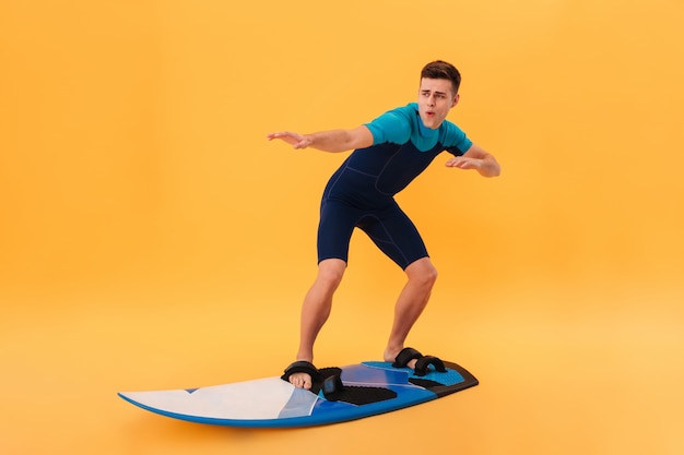 Imagen de un surfista despreocupado en traje de neopreno usando una tabla de surf como en la ola