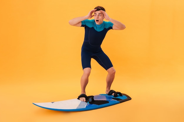 Imagen de un surfista sorprendido en traje de neopreno usando una tabla de surf como en la ola