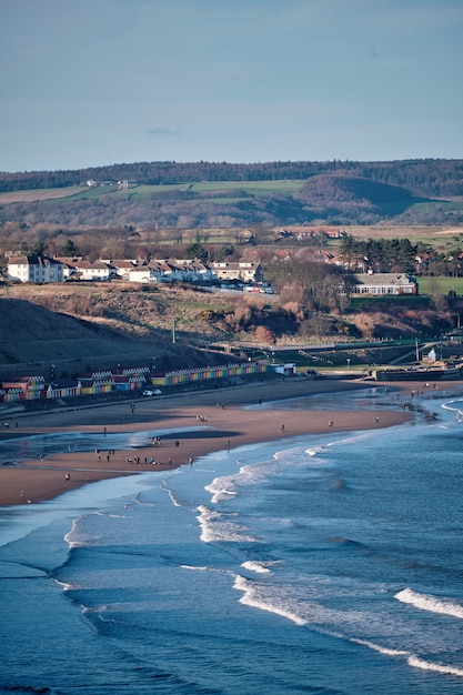 Imagen vertical de la costa de Scarborough rodeada de colinas cubiertas de vegetación en el Reino Unido