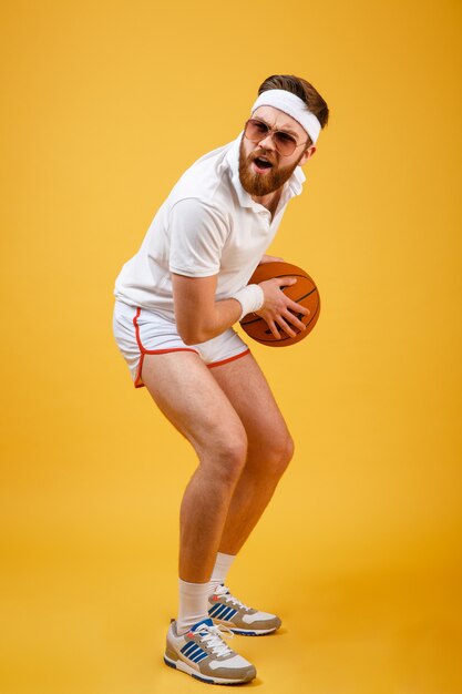 Imagen vertical de deportista concentrado en gafas de sol jugando baloncesto