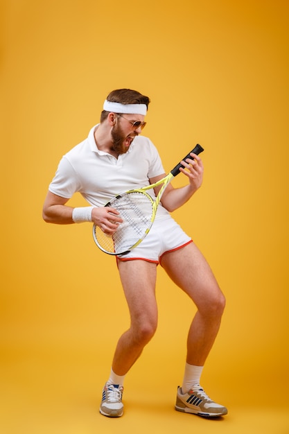 Imagen vertical del deportista divertido jugando en la raqueta de tenis