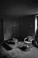 Foto gratuita imagen vertical en escala de grises del interior de una habitación pobre con una sola silla y un colchón