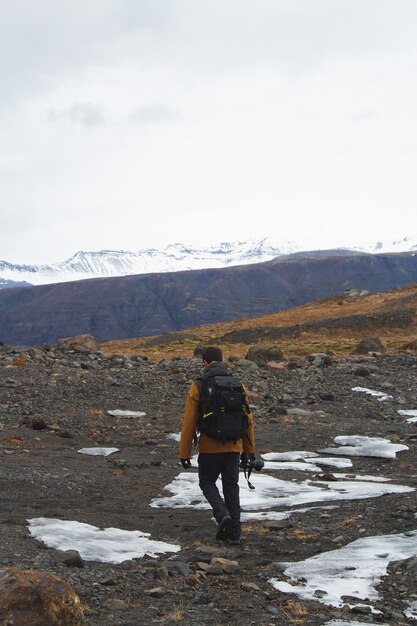 Imagen vertical de un excursionista con una cámara en las colinas cubiertas de nieve en Islandia