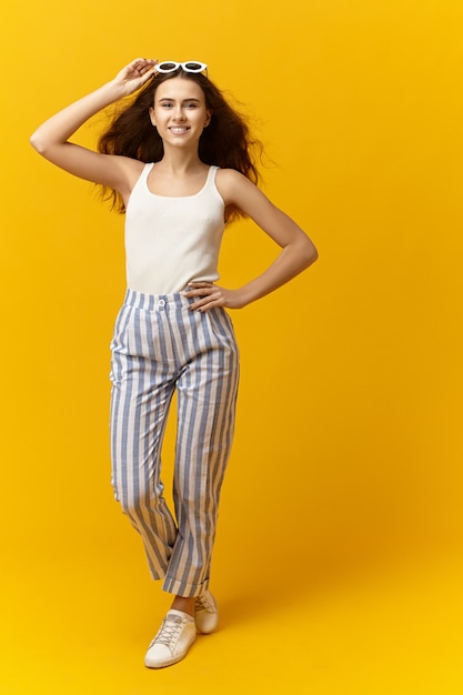 Foto gratuita imagen vertical de hermosa joven alegre vistiendo ropa y accesorios de moda fashinable