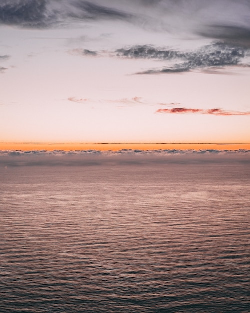 Imagen vertical de una hermosa vista al mar con olas y un horizonte naranja