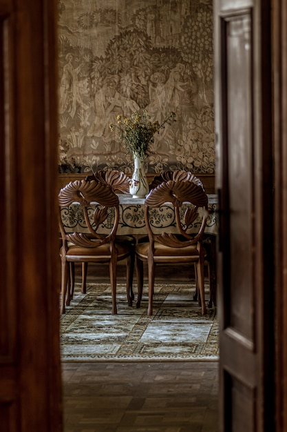 Foto gratuita imagen vertical de un lujoso comedor con sillas ornamentadas como se ve a través de una puerta abierta