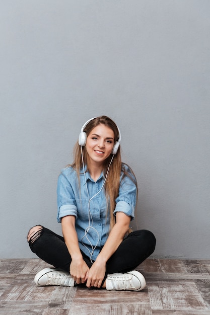 Imagen vertical de mujer escuchando música en el piso