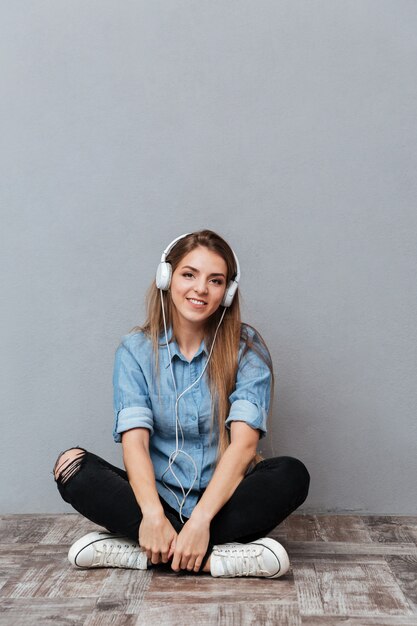 Imagen vertical de mujer escuchando música en el piso