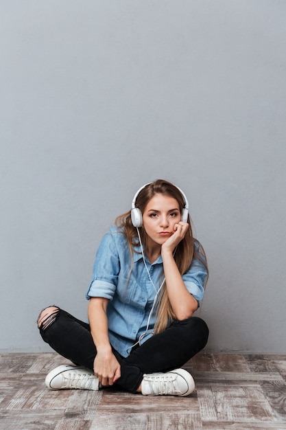 Imagen vertical de mujer escuchando música en el piso