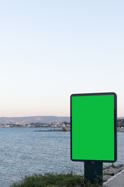 Imagen vertical de una pantalla verde para anuncios con vista al mar, un excelente espacio para su texto