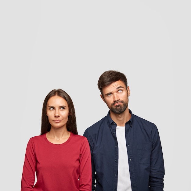 Imagen vertical de pareja pensativa tiene expresión facial confusa