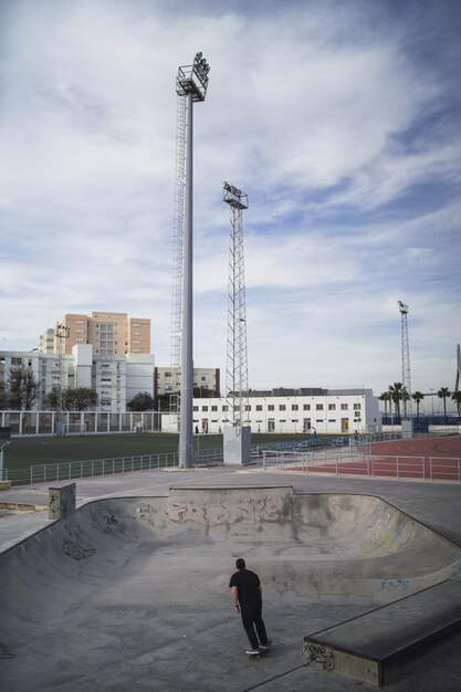 Imagen vertical de una persona en monopatín en un parque de patinaje bajo un cielo nublado durante el día