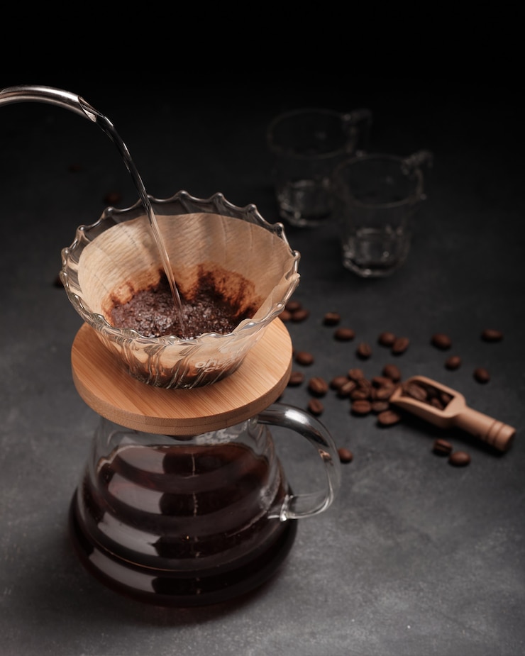 Foto gratuito imagen vertical de una persona vertiendo café en un vaso sobre un fondo negro
