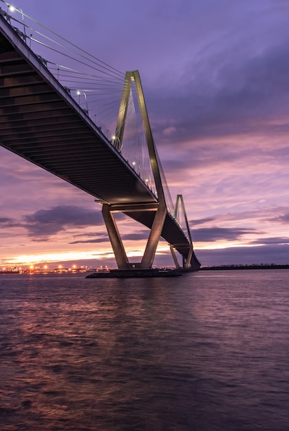 Imagen vertical de un puente sobre el mar bajo un cielo nublado durante la puesta de sol