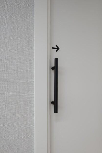 Imagen vertical de una puerta blanca cerrada con una flecha negra a la derecha