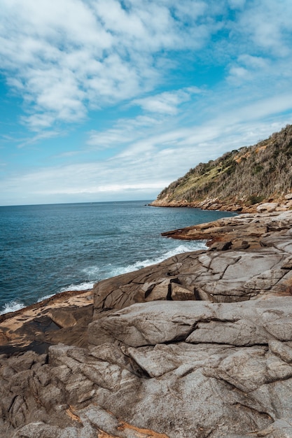 Foto gratuita imagen vertical de rocas rodeadas por el mar bajo un cielo azul y la luz del sol en río de janeiro.