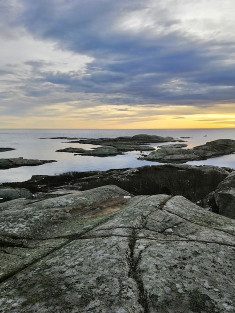 Imagen vertical de rocas rodeadas por el mar durante la puesta de sol en Rakke en Noruega