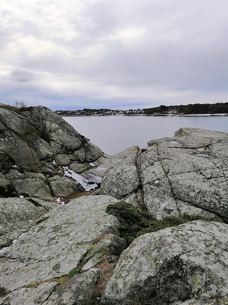 Foto gratuita imagen vertical de rocas rodeadas por el río bajo un cielo nublado en noruega