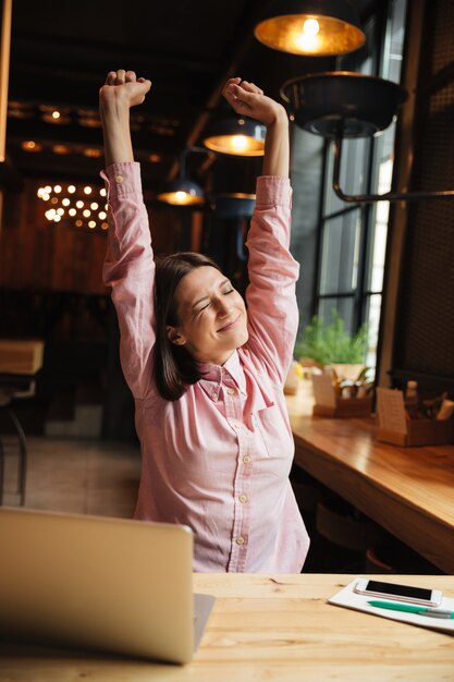 Imagen vertical de la sonriente mujer morena sentada junto a la mesa