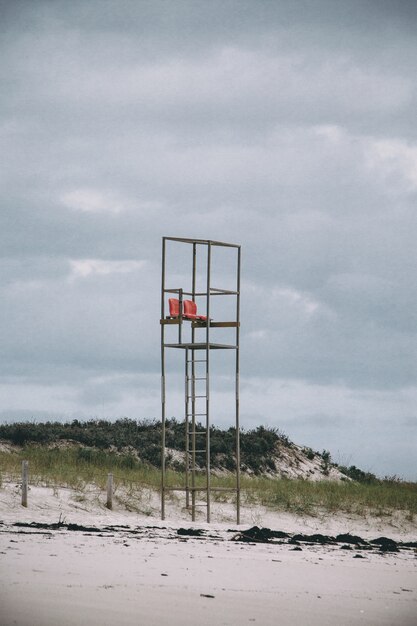 Imagen vertical de una torre de salvavidas en una playa bajo un cielo nublado durante el día