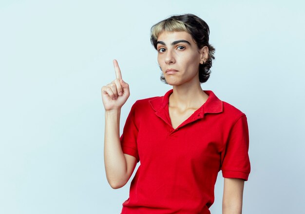 Impresionada joven con corte de pelo pixie apuntando hacia arriba