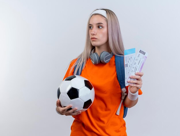 Impresionada joven deportista caucásica con auriculares alrededor del cuello con diadema de mochila