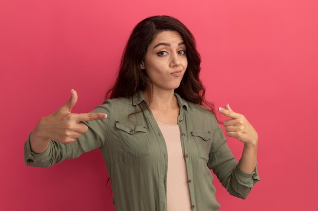 Foto gratuita impresionada joven hermosa vistiendo puntos de camiseta verde oliva en la cámara aislada en la pared rosa