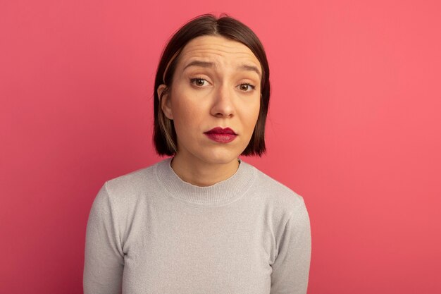 Impresionada mujer bonita caucásica mira a cámara en rosa