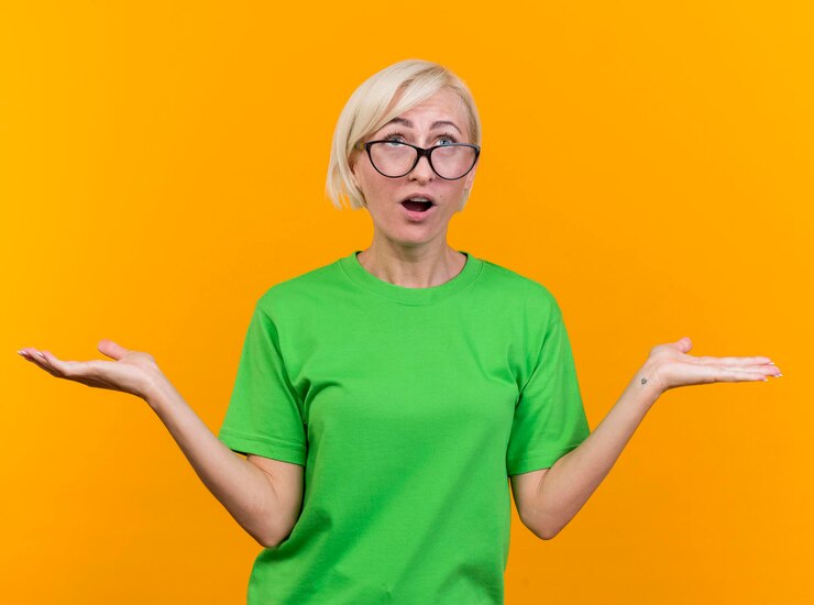 Foto gratuito impresionada mujer eslava rubia de mediana edad con gafas mostrando las manos vacías mirando hacia arriba aislado en la pared amarilla