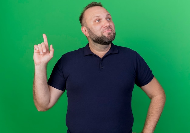 Foto gratuita impresionado hombre eslavo adulto mirando de lado y levantando el dedo aislado en la pared verde