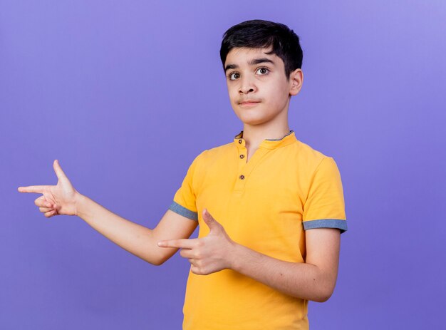 Impresionado joven caucásico apuntando al lado aislado en la pared púrpura con espacio de copia