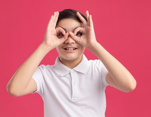 Impresionado joven caucásico haciendo gesto de mirada con las manos como binoculares