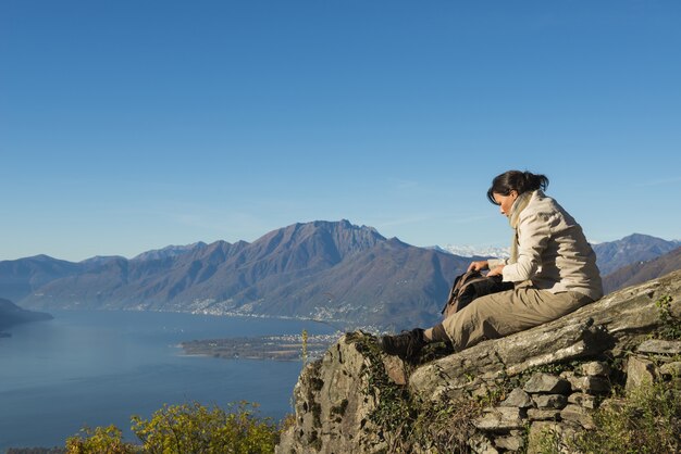 Impresionante escena de una mujer sentada en la cima de la montaña.