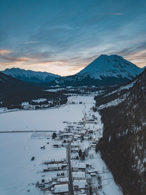 Impresionante foto de una cadena montañosa con una ciudad debajo en invierno