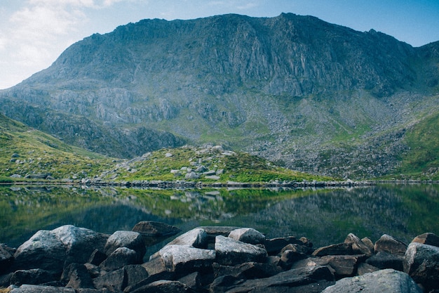 Impresionante foto de un lago cristalino rodeado de rocas y alta montaña rocosa