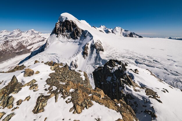 Impresionante foto de las montañas rocosas cubiertas de nieve bajo un cielo azul