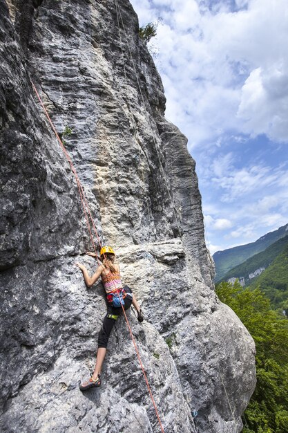 Impresionante foto de una mujer escalada en la roca alta en Champfromier, Francia