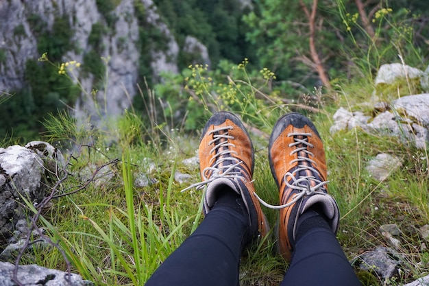 Impresionante foto de una persona sentada sobre un terreno de césped, rocas y flores en un camping