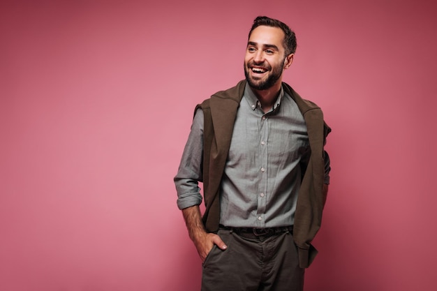 Impresionante hombre con camisa oscura y suéter riéndose de un fondo aislado