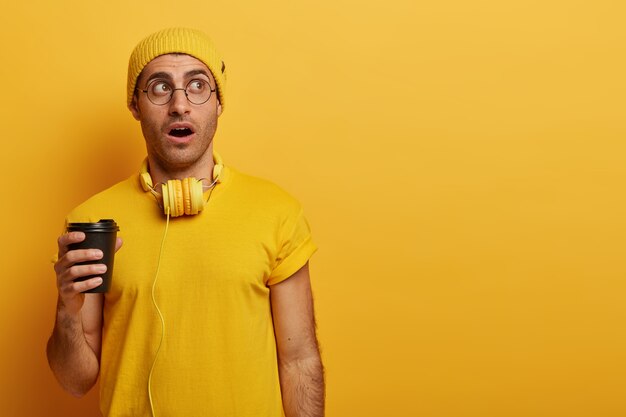 Impresionante joven se queda sin palabras, viste un sombrero amarillo y una camiseta informal