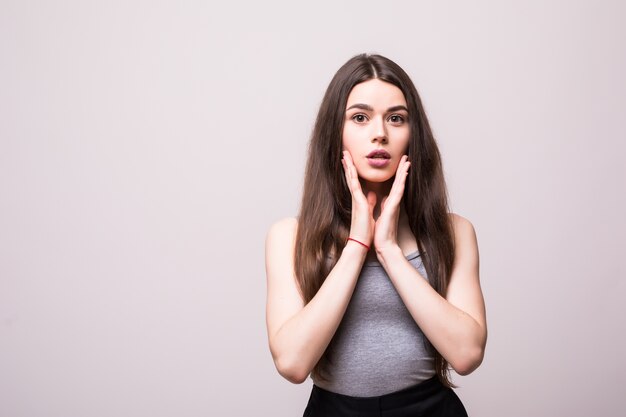 Impresionante modelo de mujer sexy alegre feliz atractivo caucásico con cabello morena está haciendo muecas, vistiendo camisa gris sin mangas, aislado