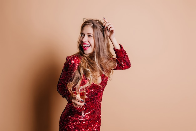 Impresionante modelo de mujer tocando su accesorio para el cabello y mirando a otro lado con una sonrisa