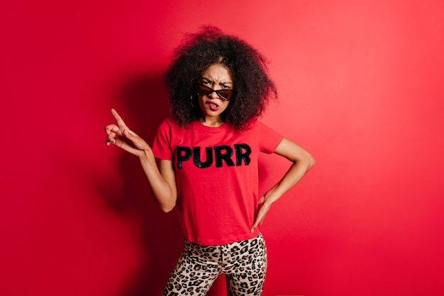 Foto gratuita impresionante mujer disgustada de pie sobre la pared roja