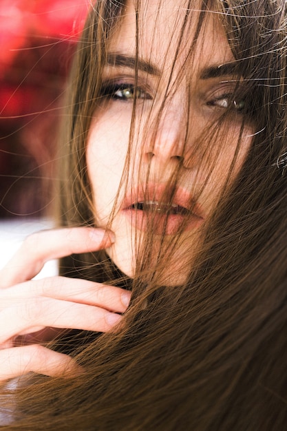 Impresionante mujer de ojos verdes se sienta ante las flores rojas