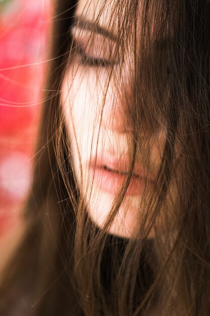 Impresionante mujer de ojos verdes se sienta ante las flores rojas