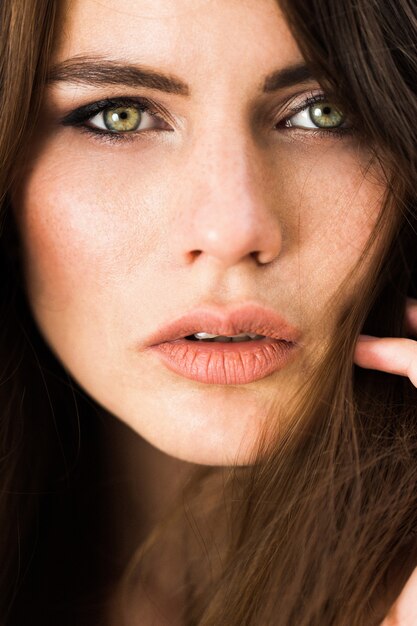 Impresionante mujer de ojos verdes se sienta ante las flores rojas