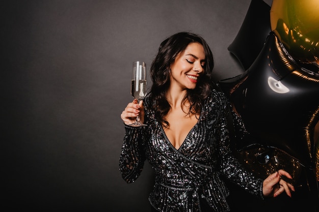 Impresionante mujer rizada disfrutando de champán