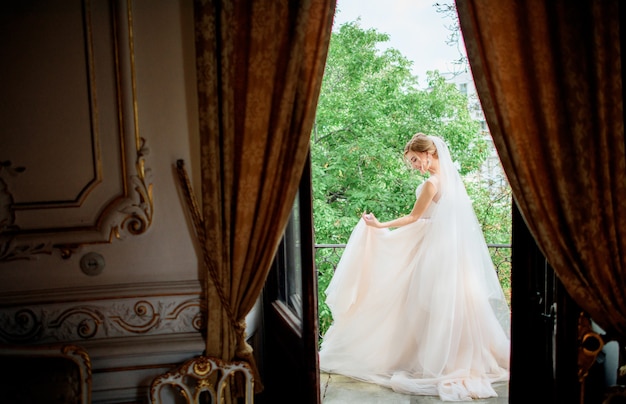 Foto gratuita impresionante novia en un vestido de novia posa en el balcón en una habitación de hotel de lujo