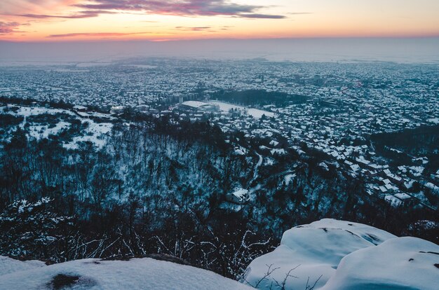 Impresionante paisaje al atardecer sobre la ciudad cubierta de nieve en invierno