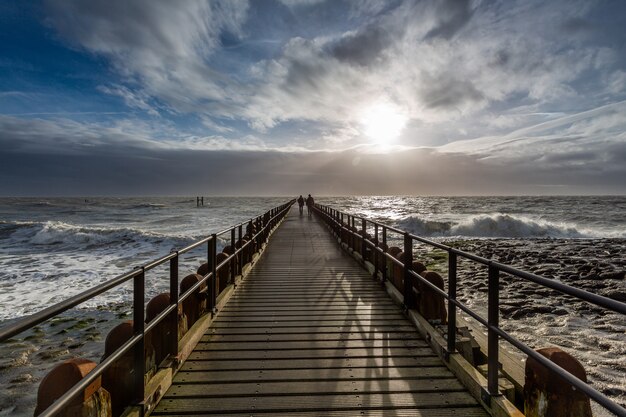 Impresionante paisaje de un amanecer sobre el muelle del océano en Westkapelle, Zelanda, Países Bajos